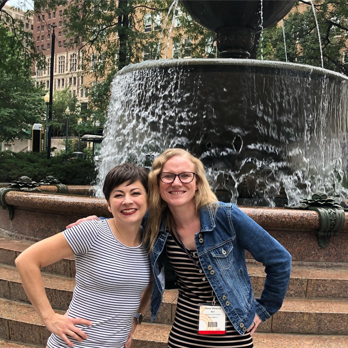 Two women standing in front of a fountain.