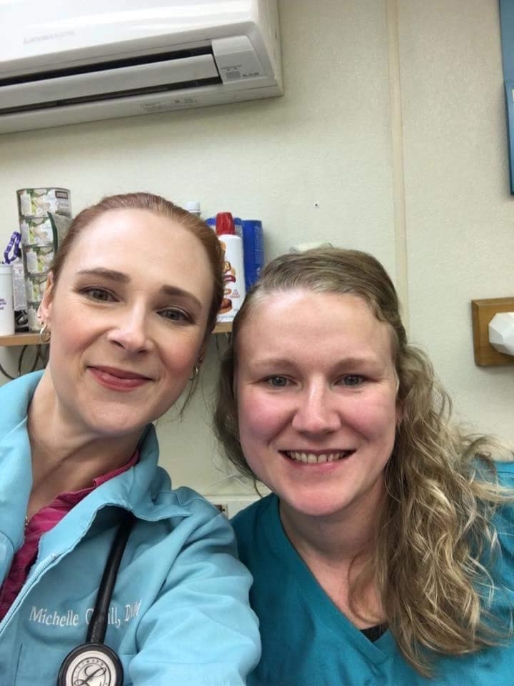 Two women in blue scrubs posing for a photo.
